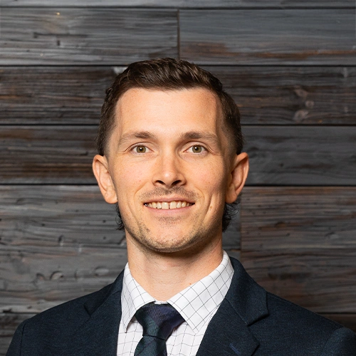 Neuropathy Doctor John Pettygrove Smiling In Front Of Wooden Wall